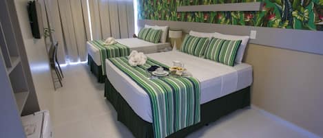 A hotel room with two beds, a TV, a window with curtains, and a tropical wallpaper.