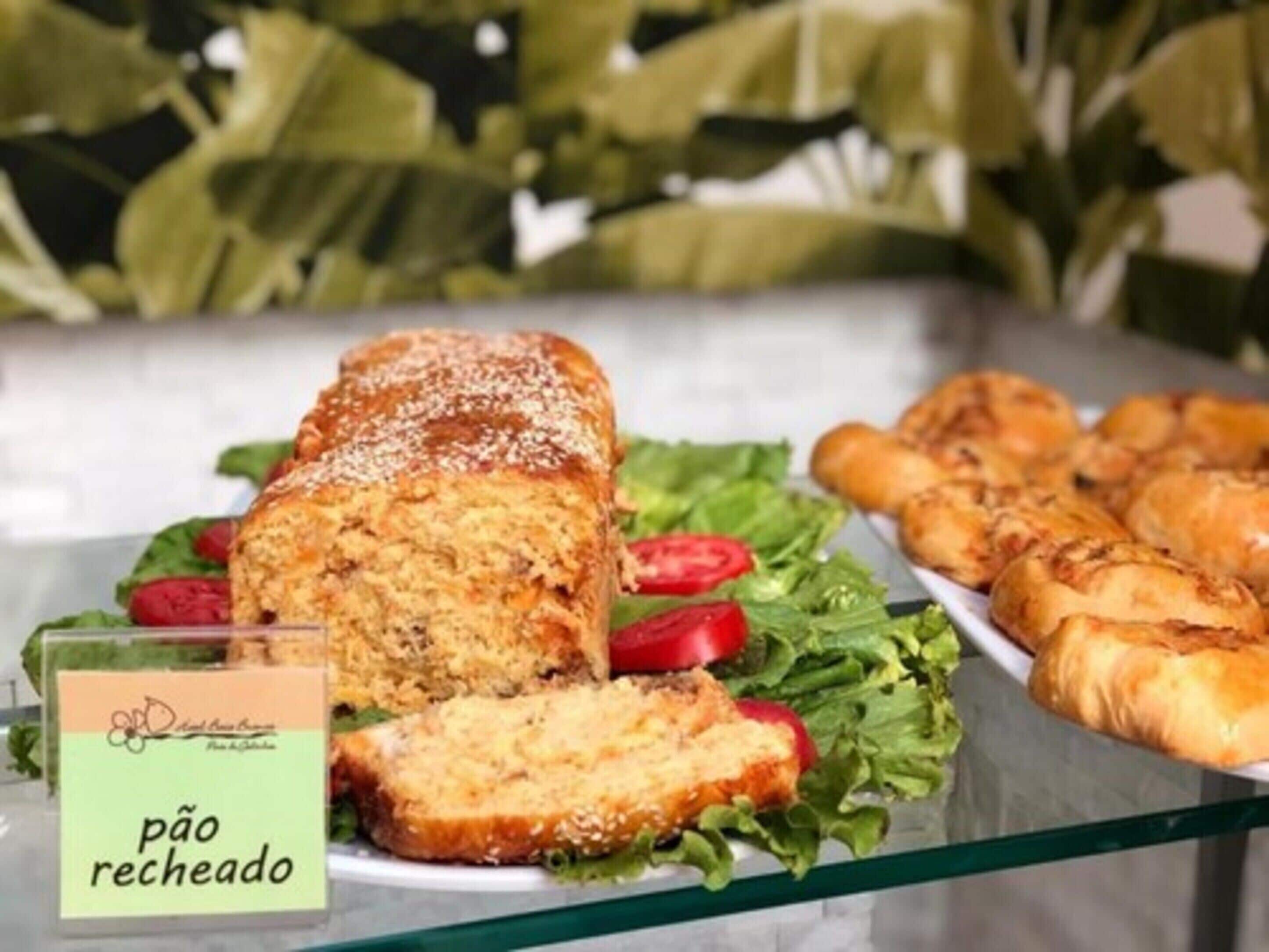 A buffet with a loaf of bread, a plate of sliced bread, and some pastries.