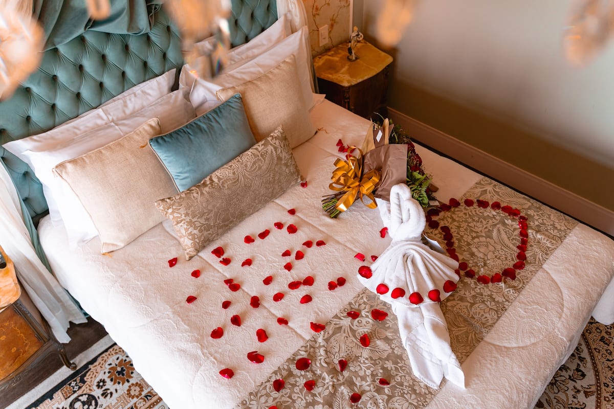 A bed with rose petals, a bouquet, and a towel, suggesting a romantic setting.