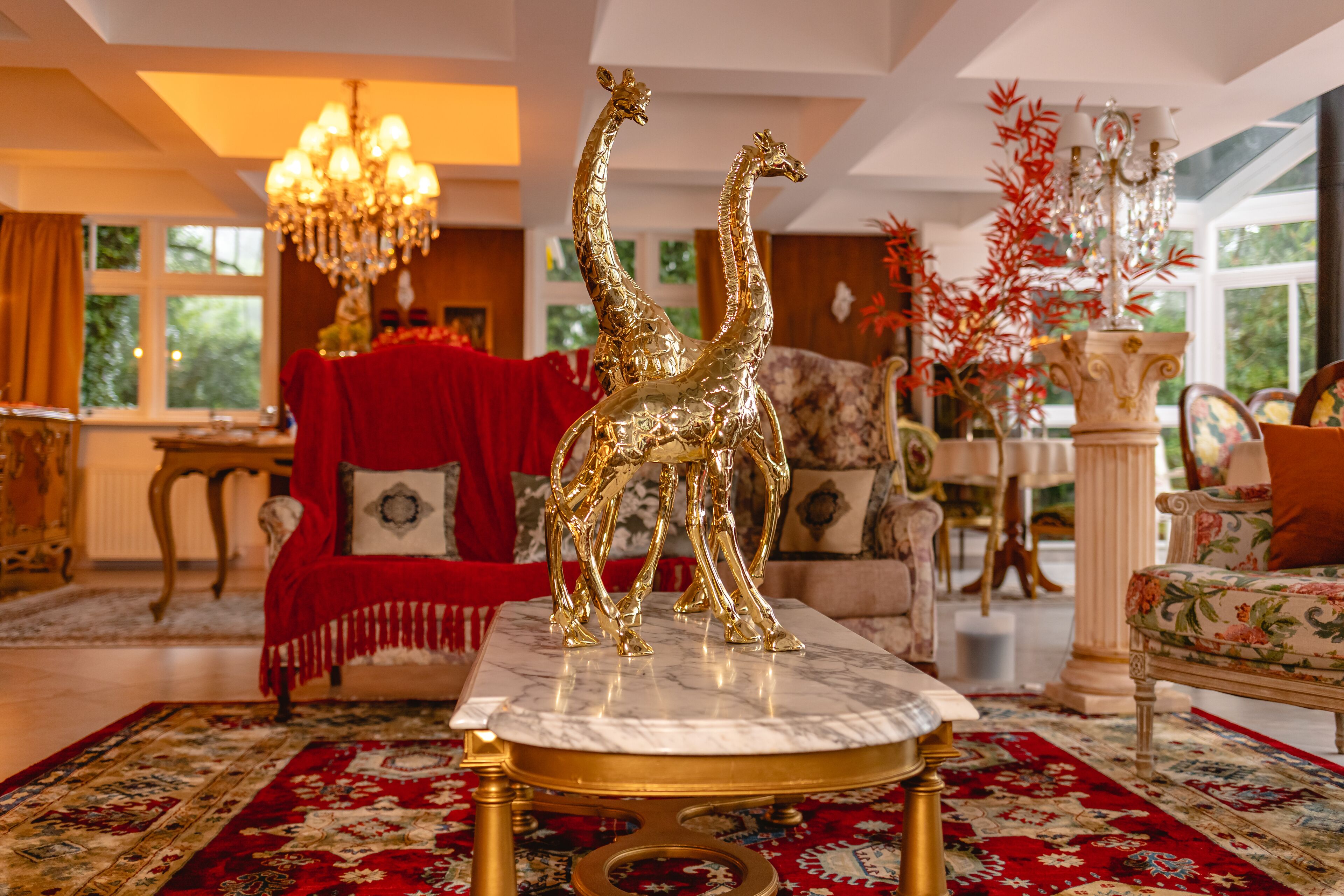 Uma sala de estar luxuosa com uma mesa de centro de mármore, um sofá vermelho e um candelabro.
