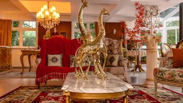 Uma sala de estar luxuosa com uma mesa de centro de mármore, um sofá vermelho e um candelabro.