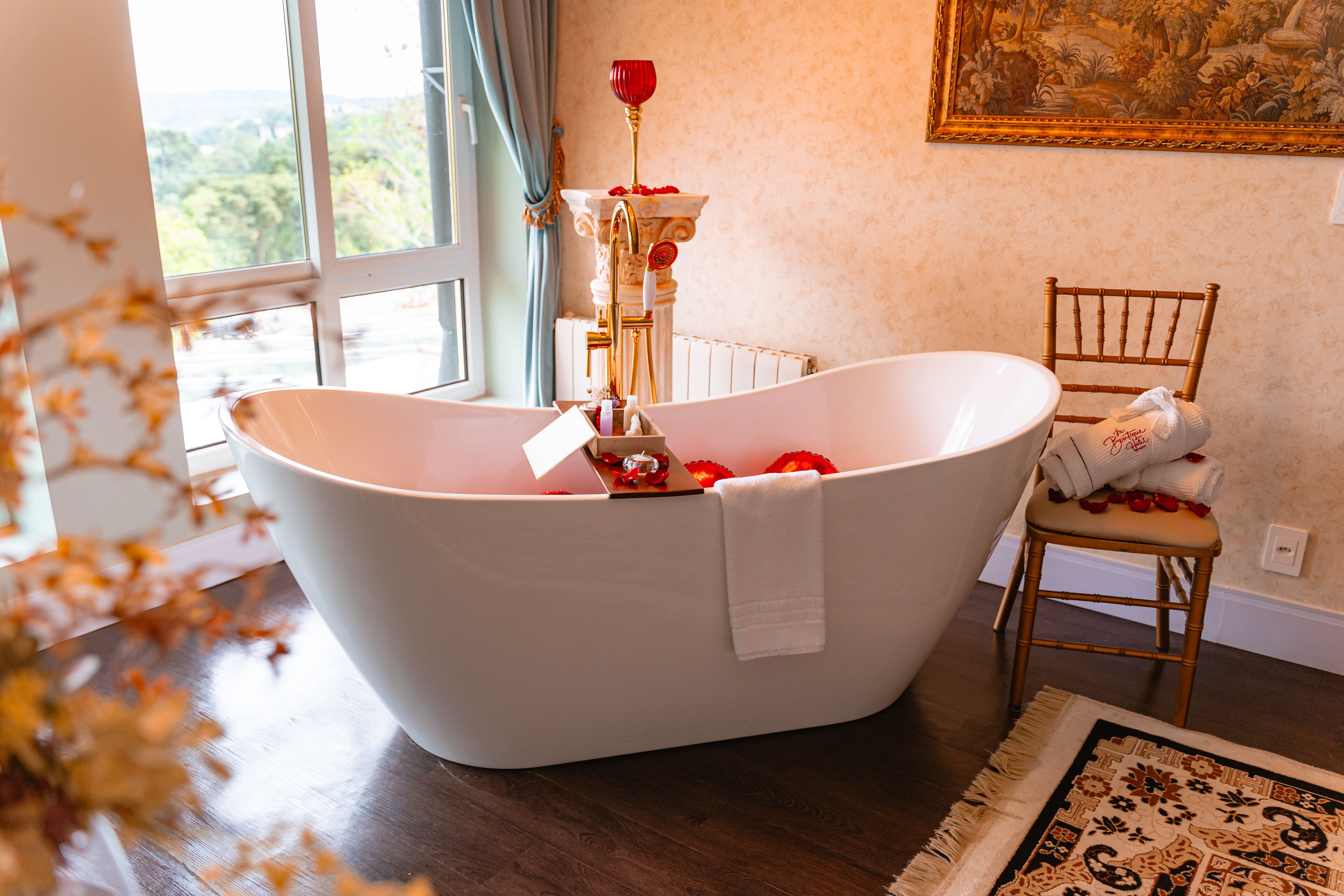 Un baño moderno con una bañera independiente, una silla de madera y una fuente decorativa.