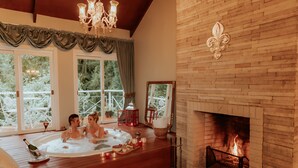 A room with a wooden floor, a fireplace, a large window with curtains, and a chandelier. - Le Boutique Hotel Gramado - Exclusivo para Casais (Gramado)