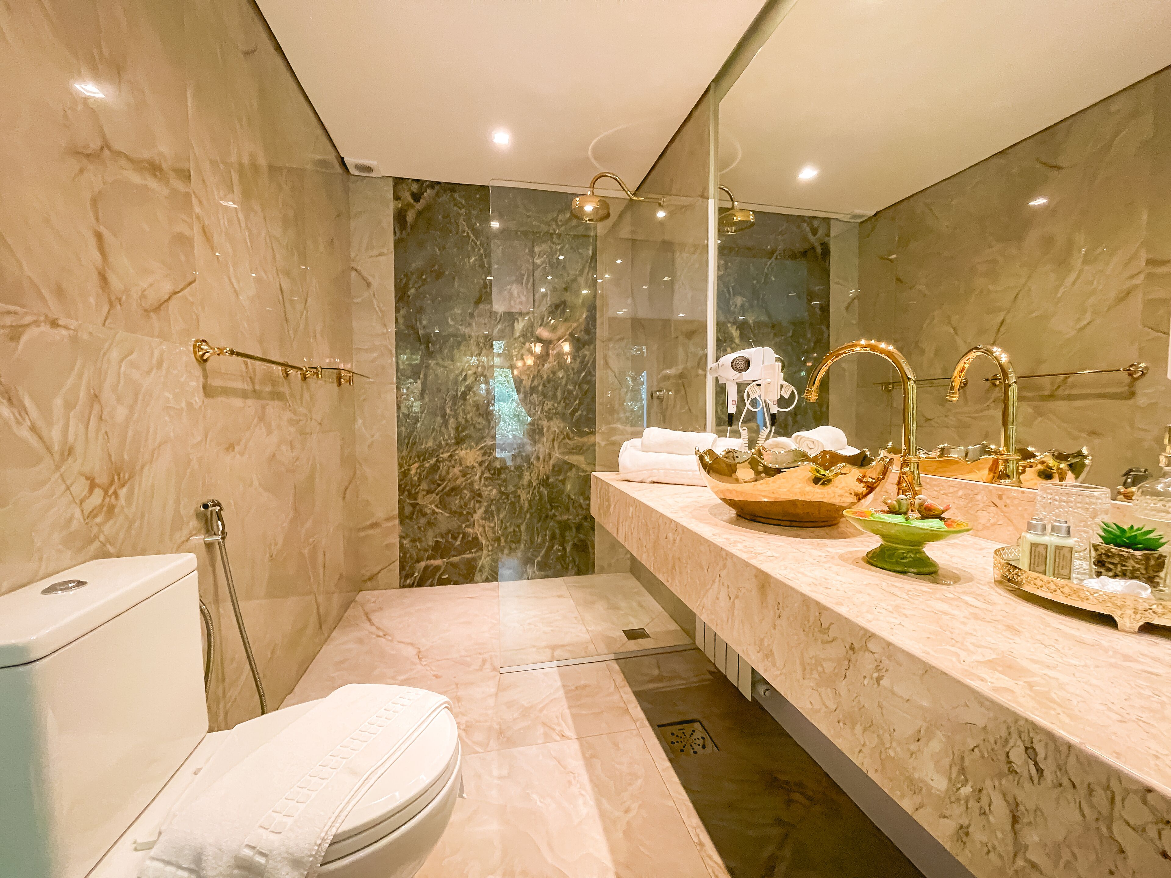 Une salle de bain moderne avec un meuble-lavabo en marbre, un grand miroir, un espace douche et des toilettes.