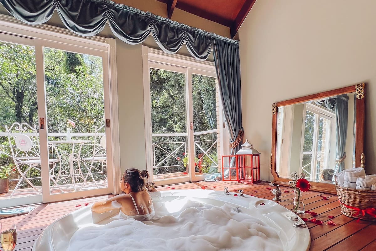 A woman relaxing in a hot tub with rose petals scattered around.