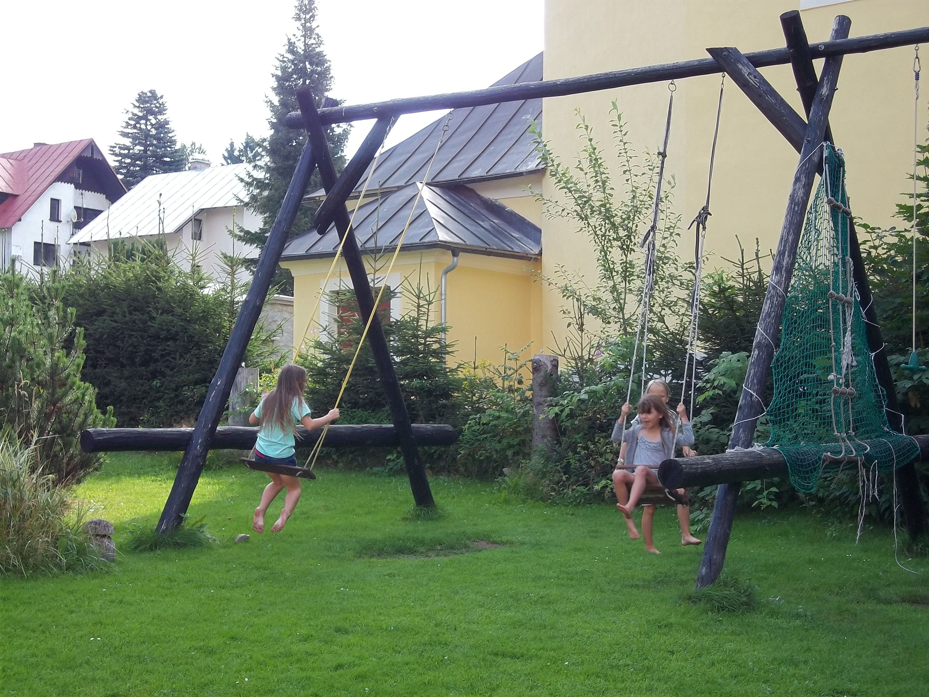 A playground with swings and a netted climbing area.