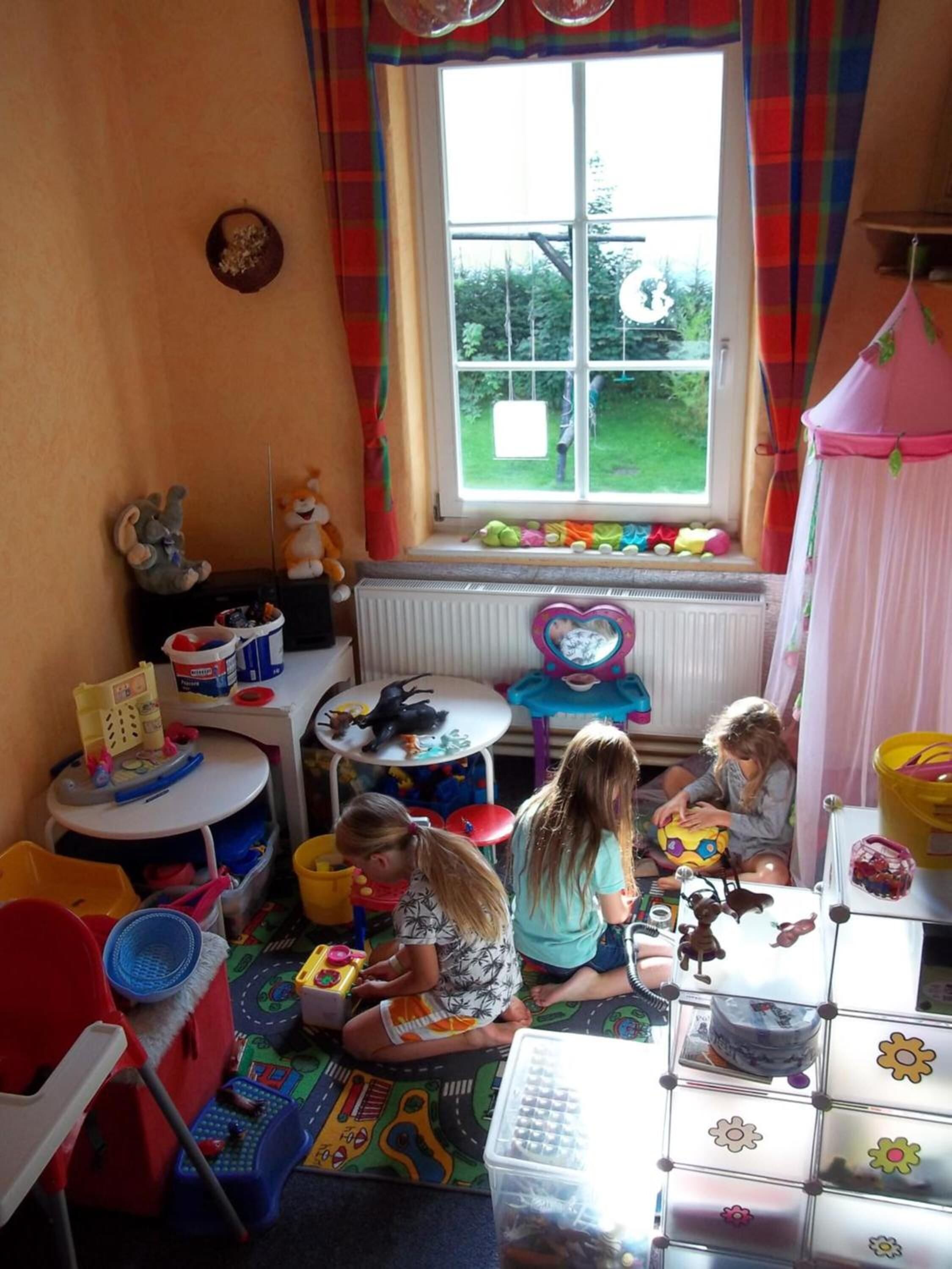 A child's playroom with toys, a window, and a radiator.