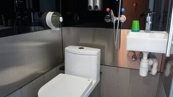 A compact bathroom with a white toilet, a sink, and a shower.