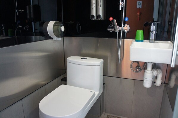 Un baño pequeño con inodoro blanco, lavamanos y ducha.