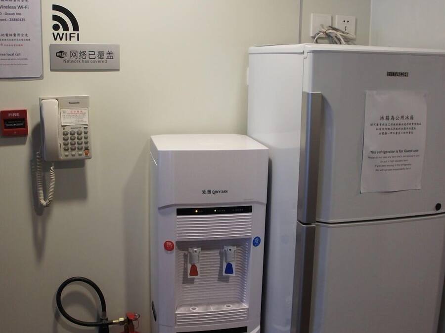A water dispenser and a refrigerator in a room with a fire alarm, a WiFi sign, and a wall decal.
