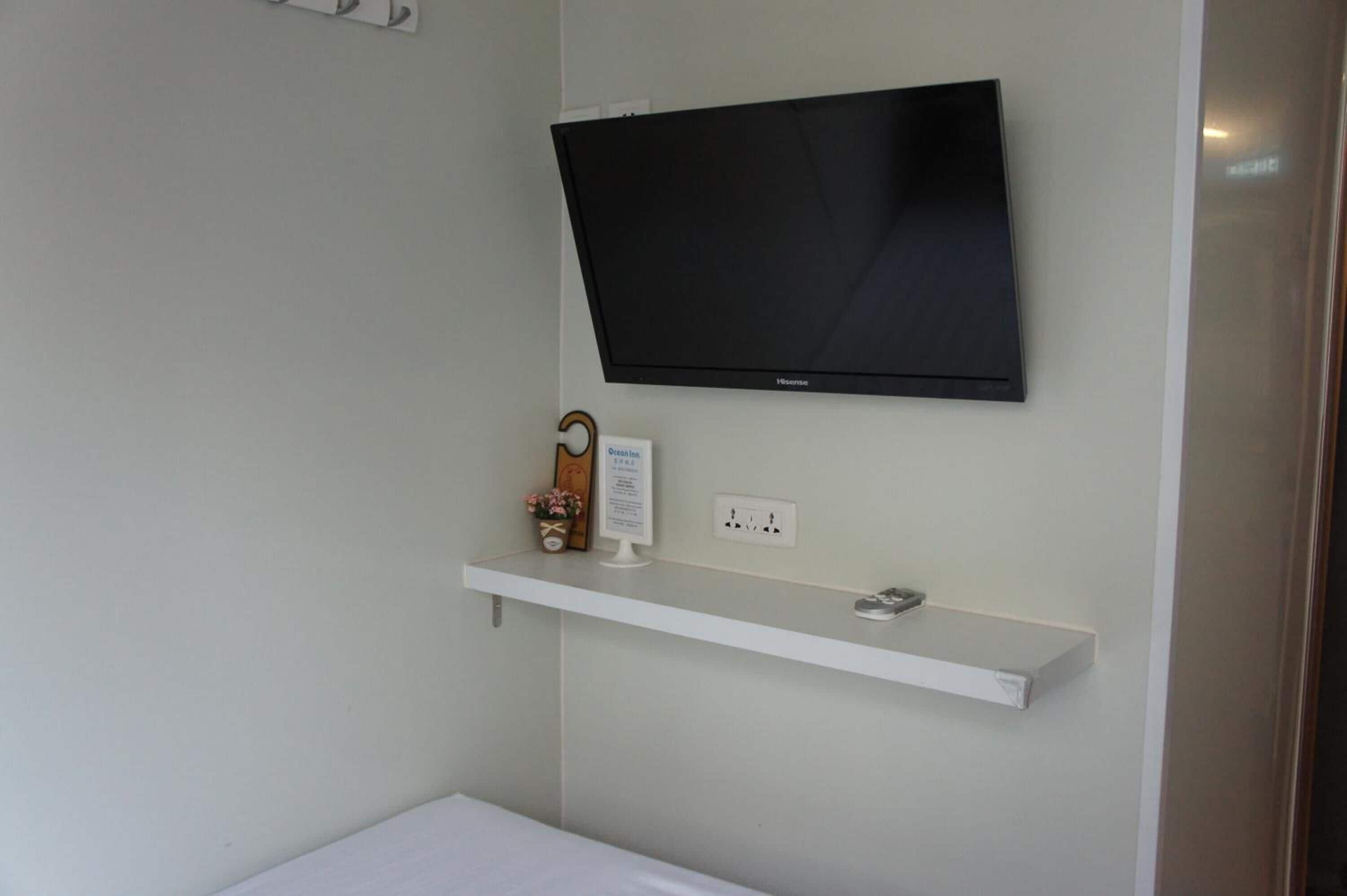 Una stanza con TV a schermo piatto montata, un piccolo ripiano con un oggetto decorativo e una presa di corrente.
