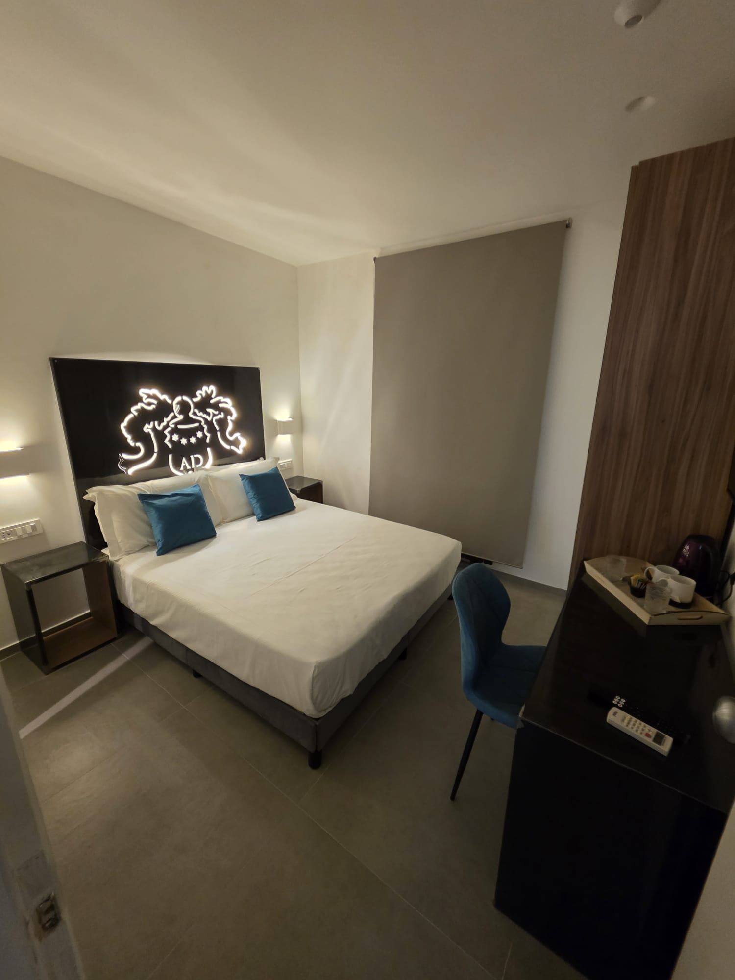 A modern bedroom with a bed, bedside tables, a desk, and a chair.