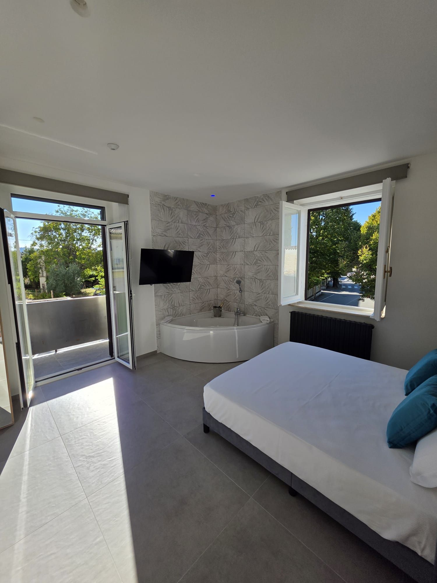 Un dormitorio moderno con una cama grande, una bañera y una televisión.