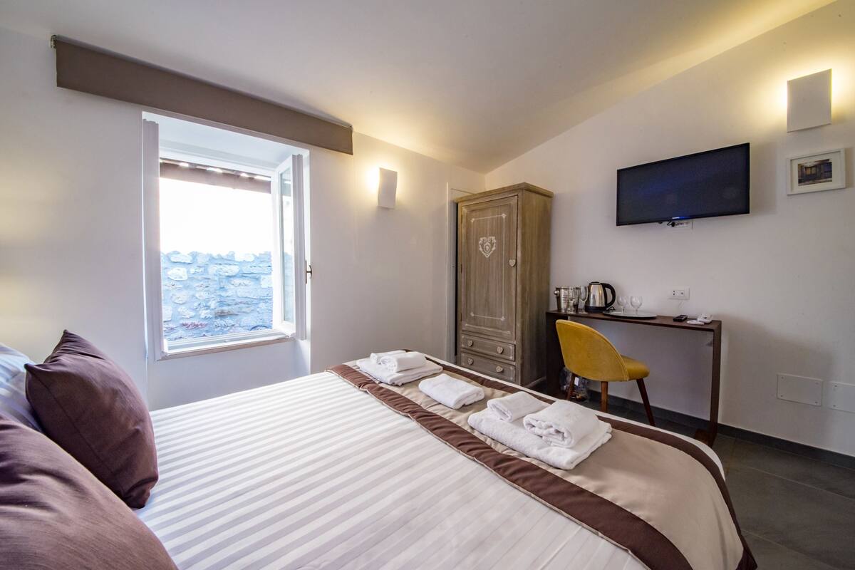 A hotel room with a bed, a desk, a chair, a television, and a wardrobe.