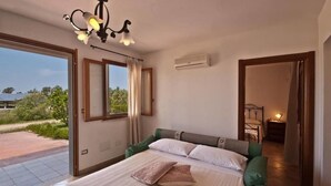 A bedroom with a bed, a chandelier, an air conditioning unit, and a view of the outdoors. - Agriturismo Sa Suerera (Olmedo)