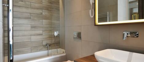Un baño moderno con una pared de madera, un inodoro blanco, una bañera y un espejo grande.