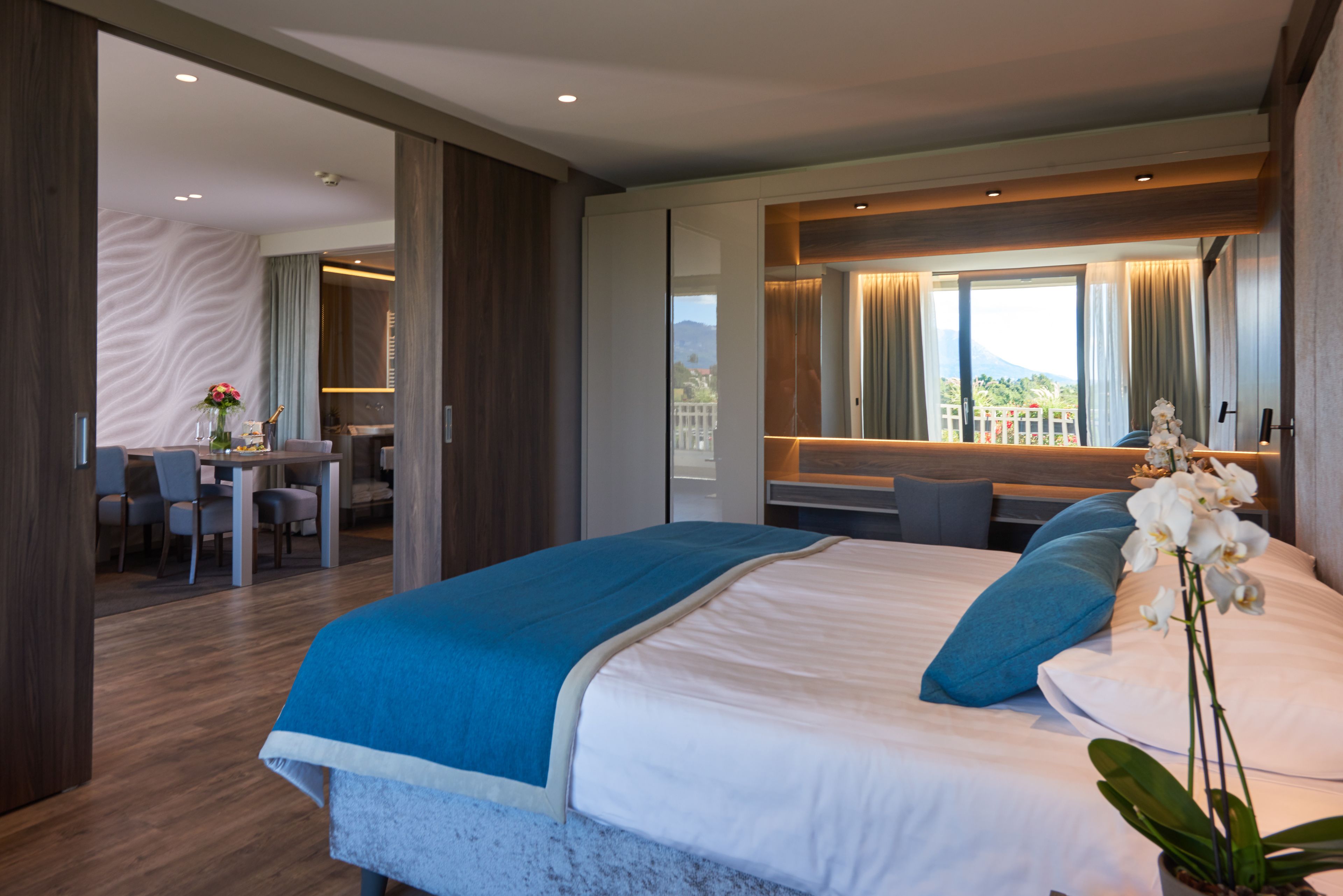 Quarto de hotel moderno com uma cama grande, uma escrivaninha e vista para as montanhas.