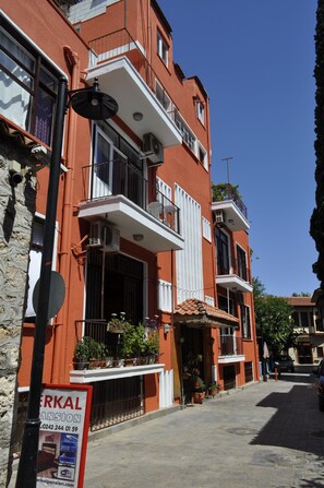 A red building with balconies, a signboard, and potted plants. - Erkal Pansion (Antalya)