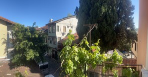 Un patio con un edificio blanco, un árbol grande y una autocaravana estacionada.