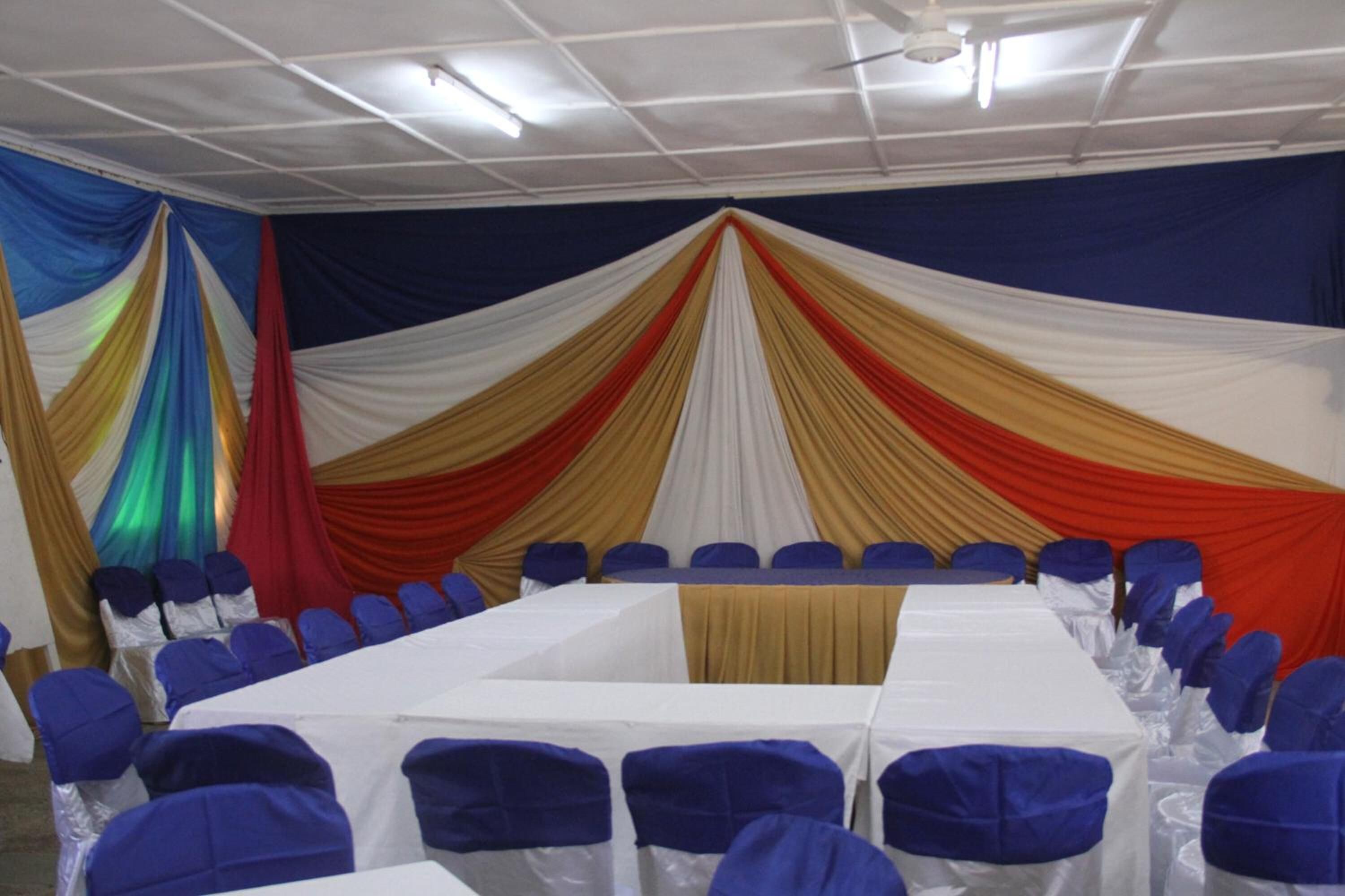 A conference room with a long table, blue chairs, and draped fabric on the walls.