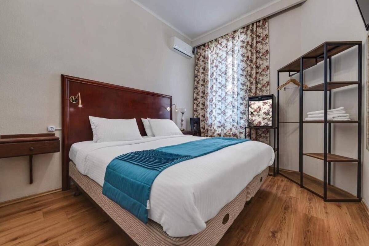 A neatly made bed with a wooden headboard, a bedside table, and a built-in wardrobe with shelves.