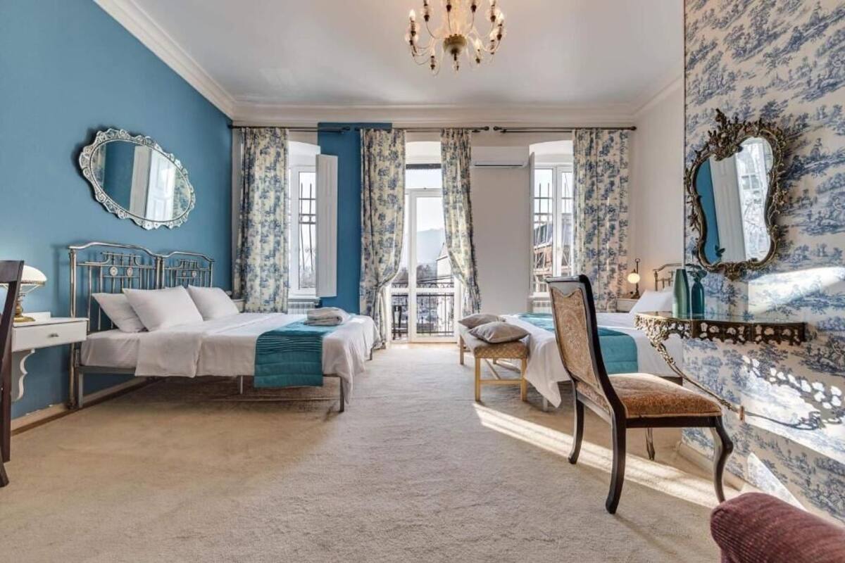 A room with two beds, a chair, a mirror, and a chandelier.
