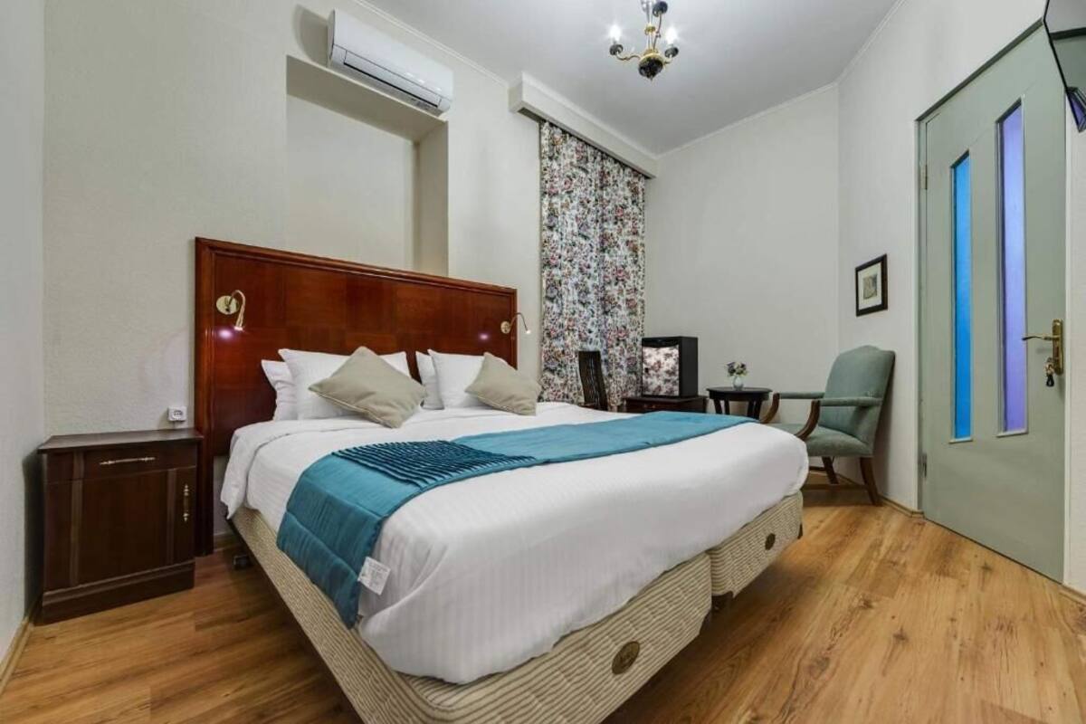 A neatly arranged bedroom with a large bed, a small desk, a chair, and a wardrobe.