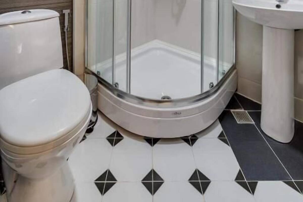 A modern bathroom with a glass-enclosed shower, a white toilet, and a sink.