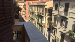 A narrow street between buildings with balconies, a clear sky, and a distant mountain. - Liola Home (Palermo)