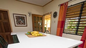 A kitchen with a white countertop, a dining table with chairs, and a window with blinds.
