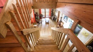 A wooden staircase leading to a living area with a view of the outside.
