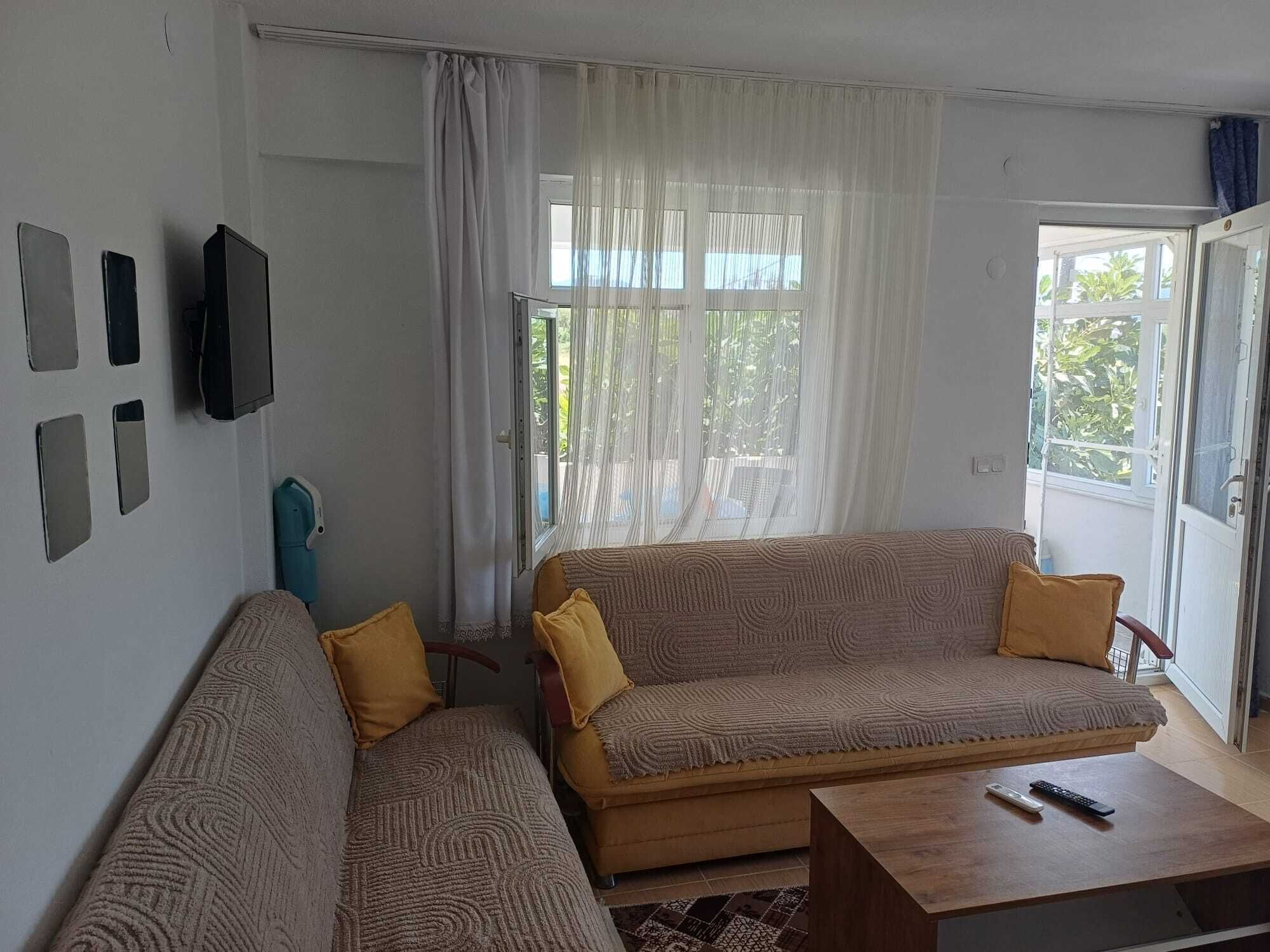 A living room with a sofa, a coffee table, and a TV mounted on the wall.