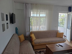 A living room with a sofa, a coffee table, and a TV mounted on the wall. - Elite Apart Pansiyon (Gökçeada)