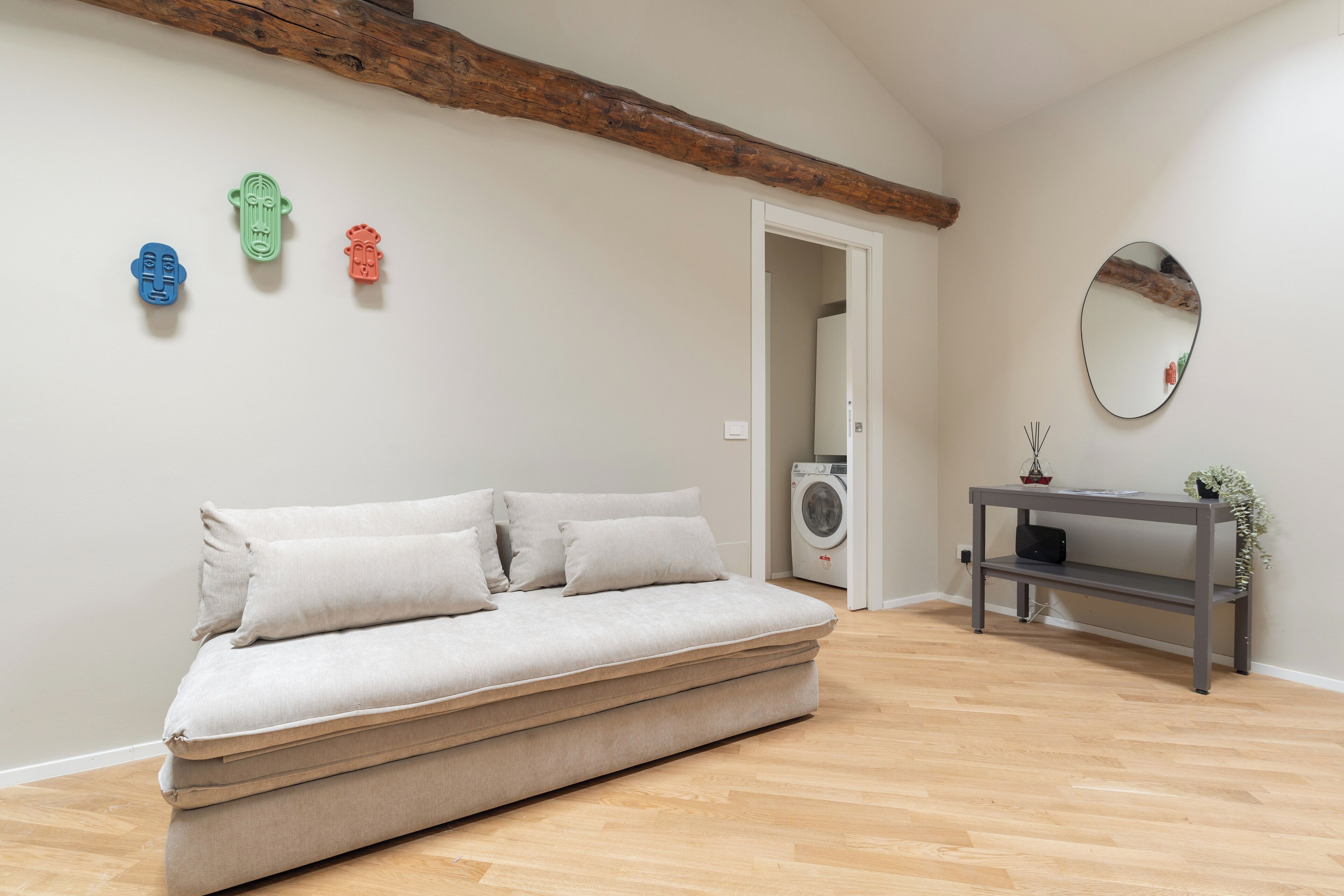 A minimalist room with a sofa, a console table, and a mirror.