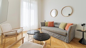 A modern living room with a sofa, two round mirrors, a chair, and a small table. - Brera Apartments in Porta Venezia (Milan)