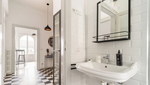 A modern bathroom with a white sink, black-framed mirror, and checkered floor tiles. - Brera Apartments in Porta Venezia (Milan)