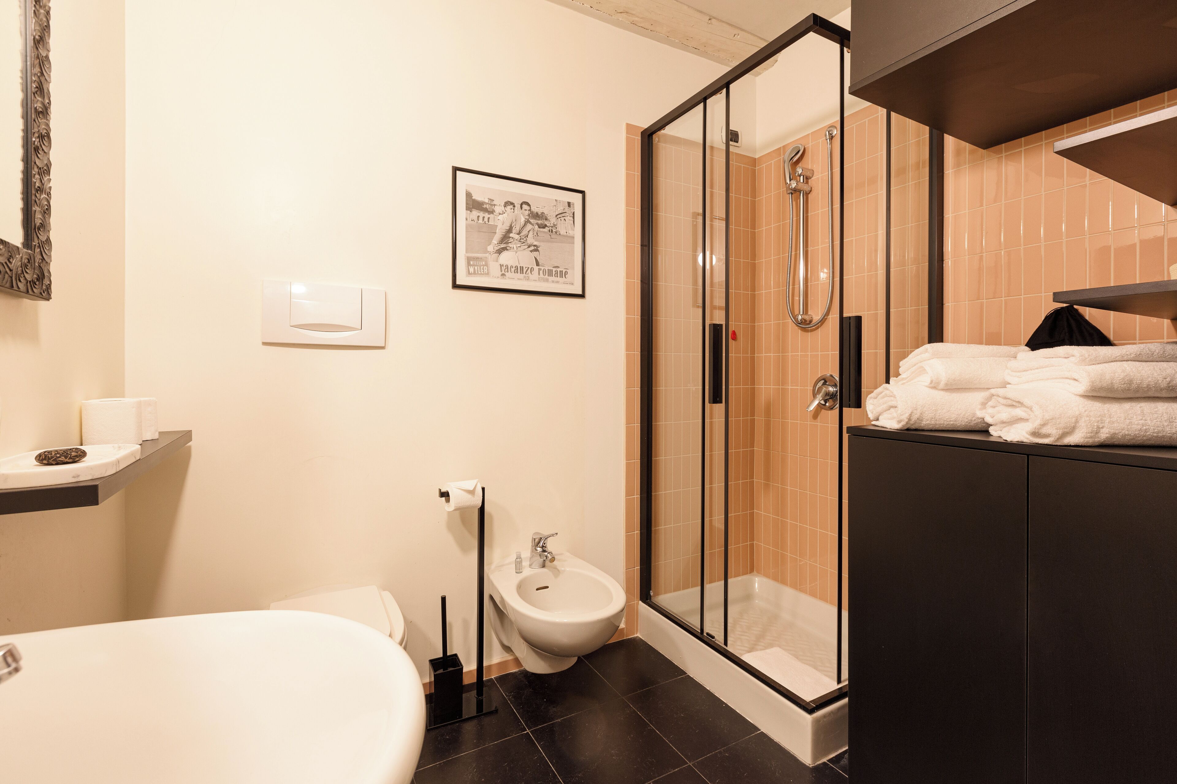 A modern bathroom with a bathtub, toilet, bidet, and a glass-enclosed shower area.