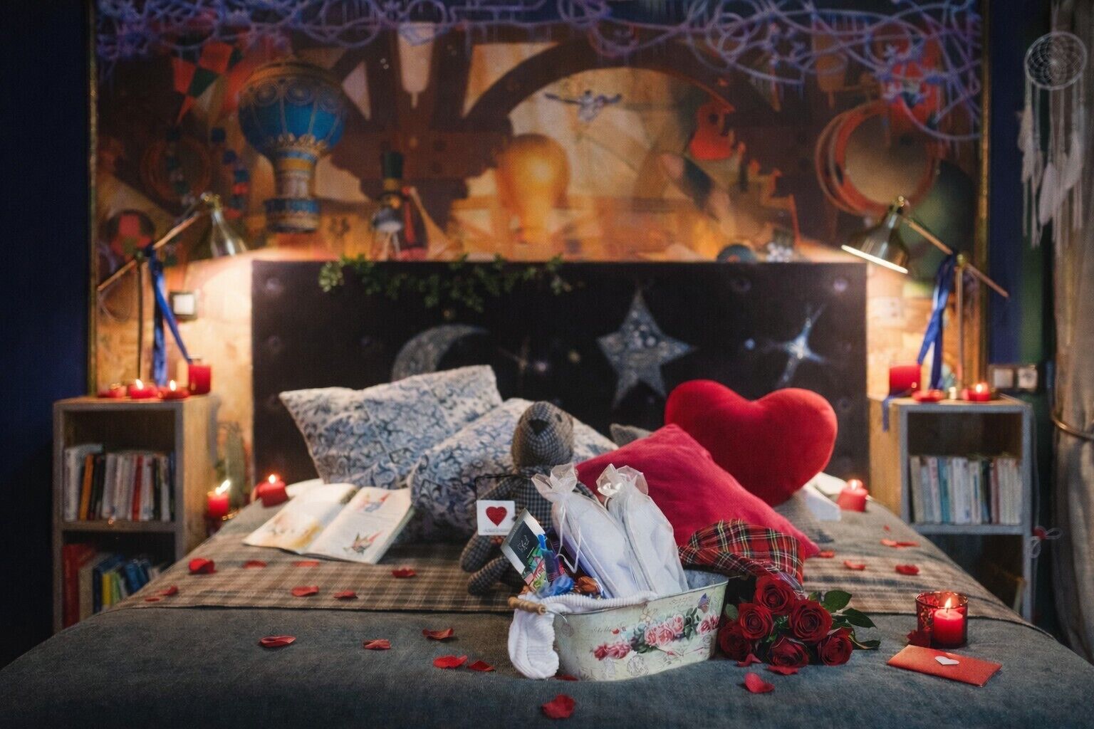 A cozy bedroom with a bed, pillows, a teddy bear, a heart-shaped pillow, a basket of roses, and a bookshelf.