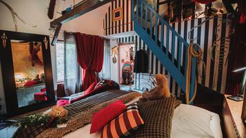 A cozy bedroom with a bed, pillows, a teddy bear, a mirror, and a staircase.