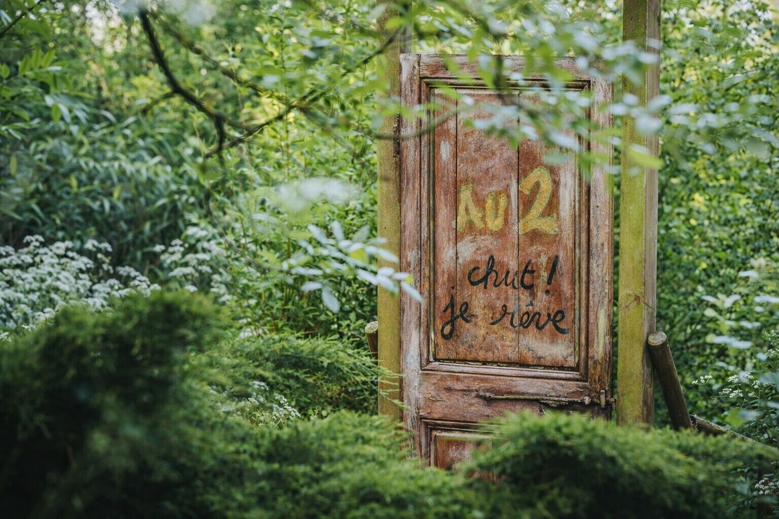 A rustic wooden door with graffiti that reads "NO 2 CHUT! je rime".