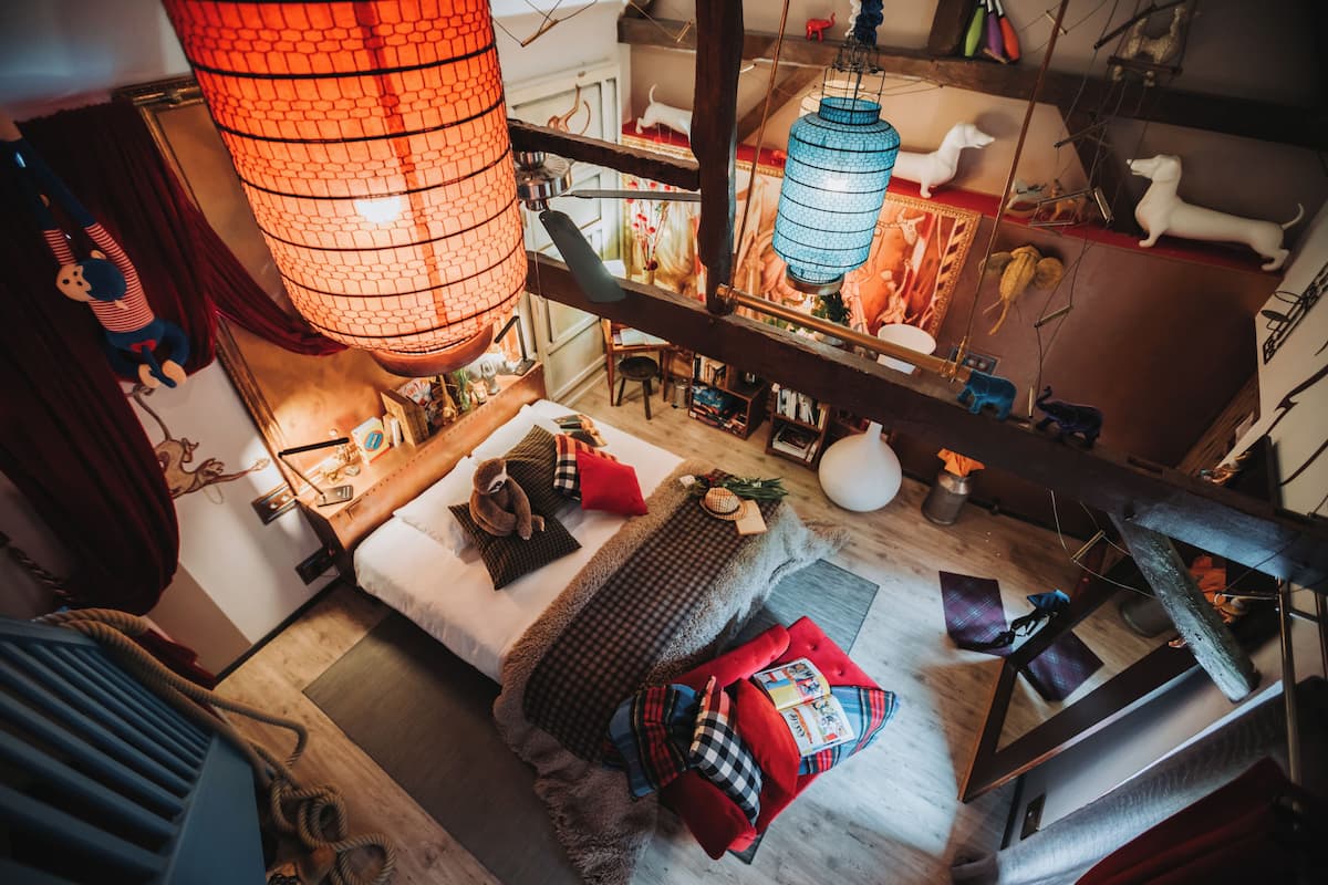 Um quarto acolhedor com cama, piso de madeira e luminária pendente.