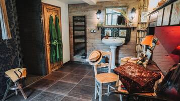 Un baño con pared de madera, un lavamanos blanco, un espejo y un perchero con toallas verdes.
