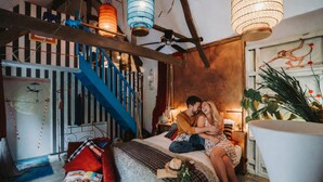 Un dormitorio acogedor con una cama, una escalera azul y faroles colgantes.