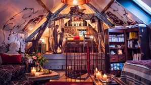 Un acogedor cuarto ático con una cama, una zona de lectura con estanterías y un techo decorativo.