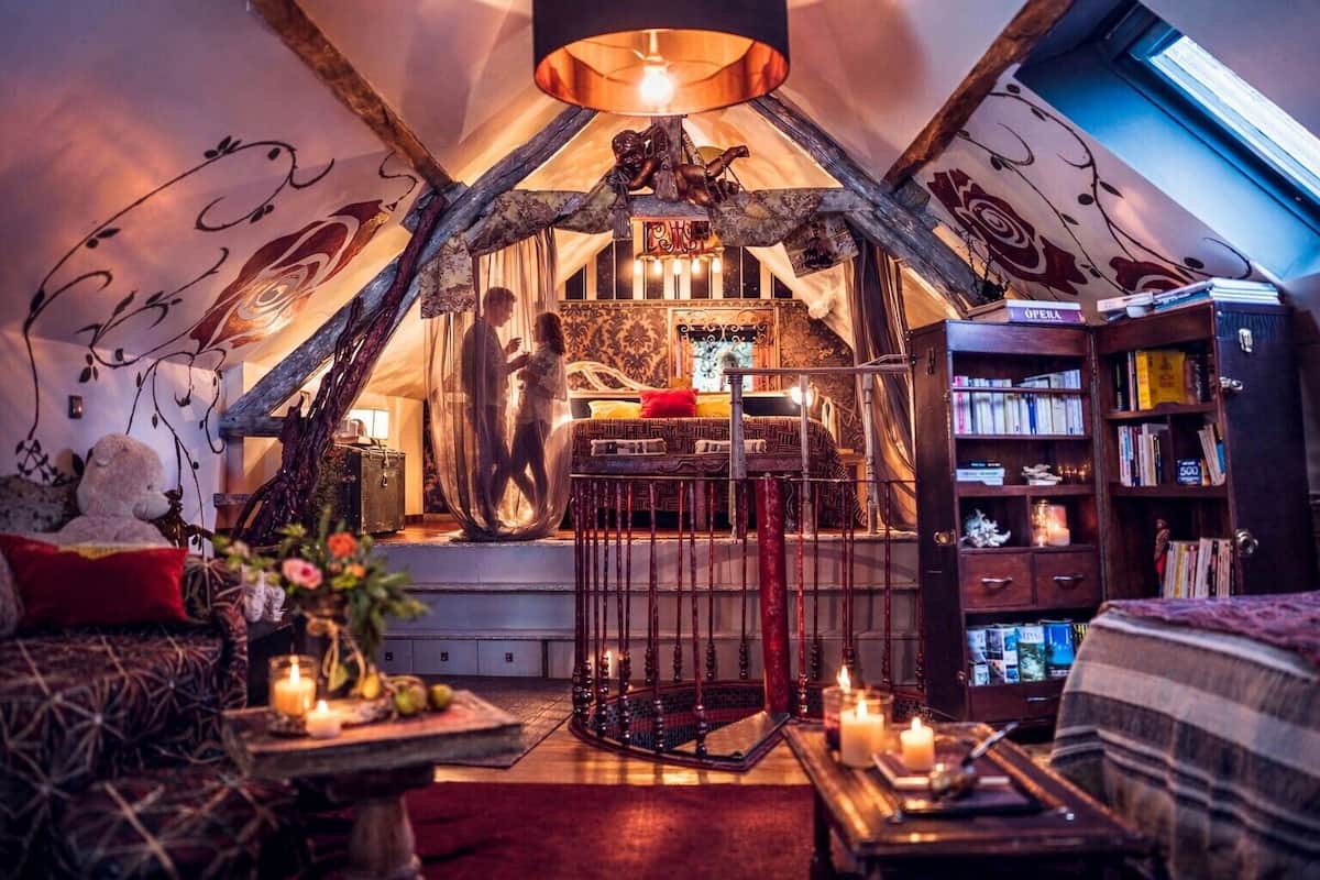 Um quarto de sótão acolhedor, com cama, um espaço de leitura com estantes e teto decorativo.