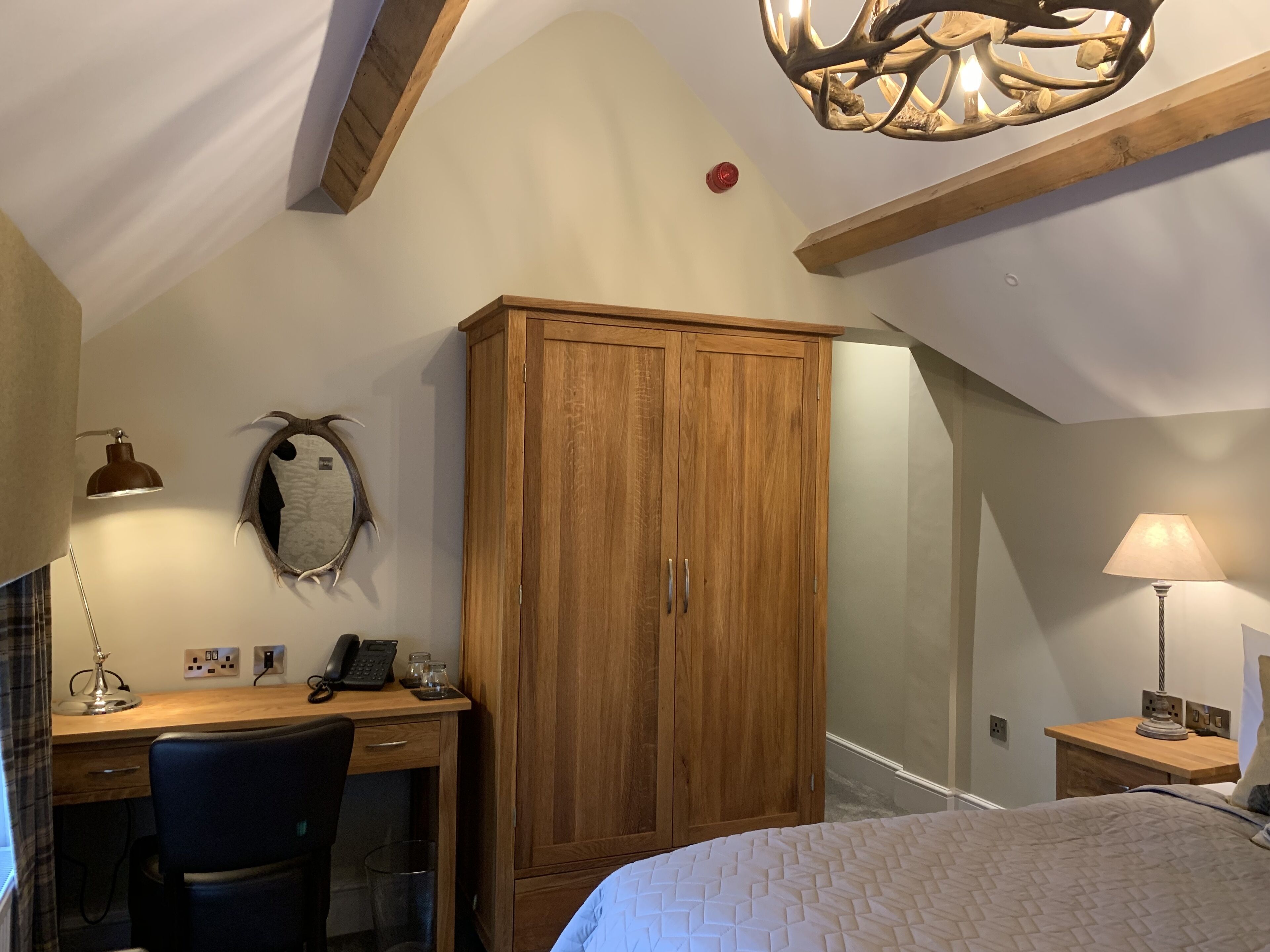 Ein Schlafzimmer mit einem Holzschrank, einem Schreibtisch mit Stuhl, einem Bett und einer Kristallleuchter.