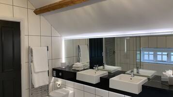 A modern bathroom with two sinks, a toilet, and a towel rack.
