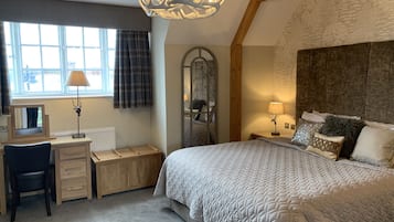 Ein Schlafzimmer mit einem großen Bett, einem Schreibtisch, einem Stuhl, einem Spiegel und einer Deckenleuchte.