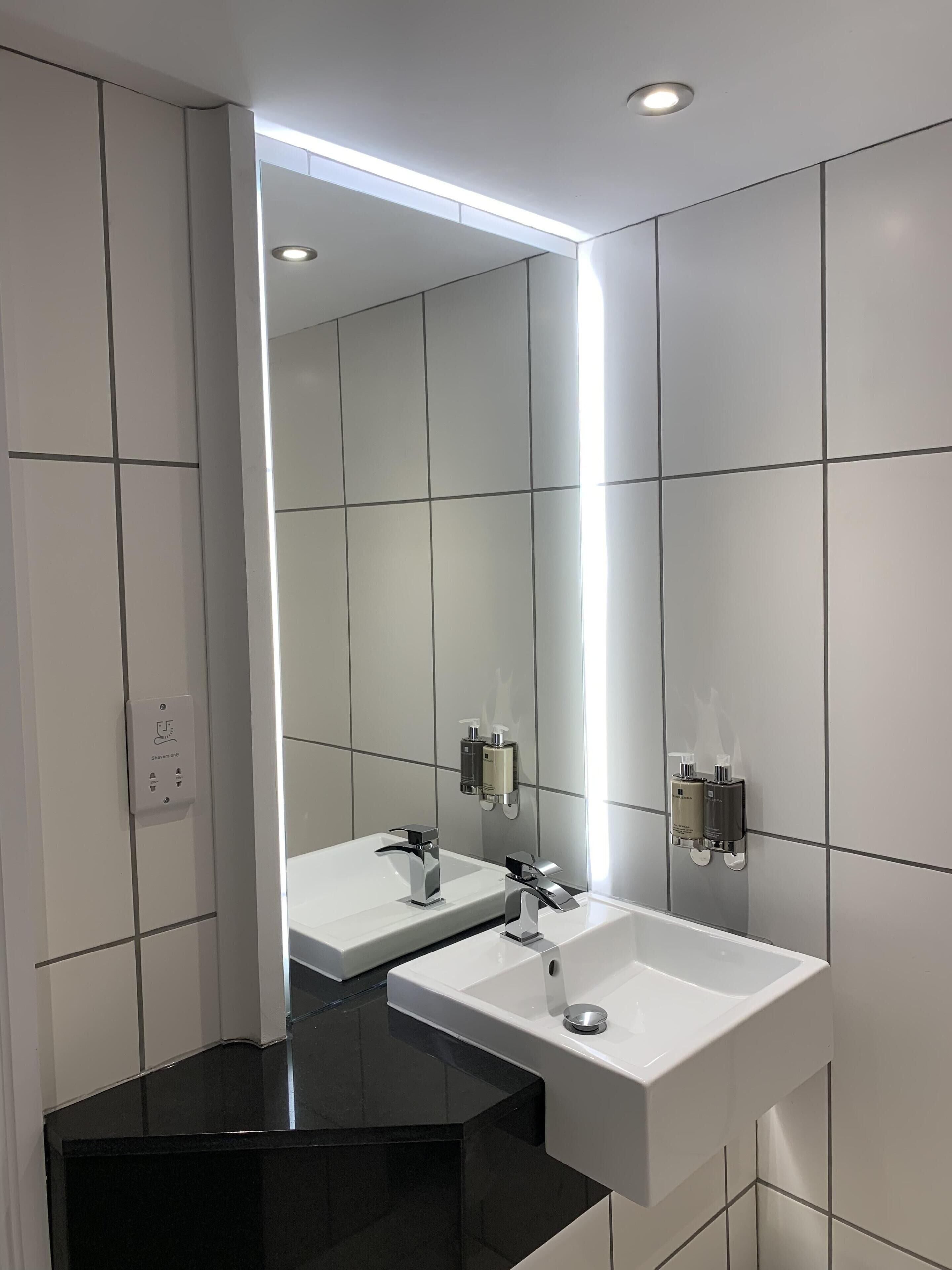 Un baño moderno con encimera negra, dos lavamanos y un espejo grande.