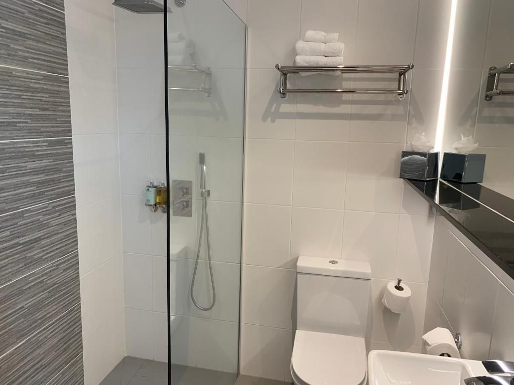 Un baño moderno con cabina de ducha de vidrio, inodoro y lavamanos.